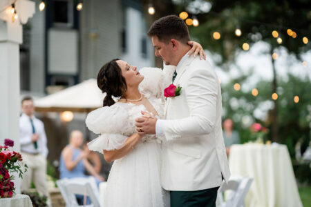 Bride and groom share a joyful first dance under string lights, with guests and flowers at their dreamy New Orleans wedding.