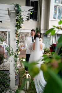 Bride and groom under a white pergola at an outdoor New Orleans wedding, with greenery and candles for inspiration.