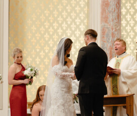 Bride and groom exchange vows in an ornate Mobile Alabama church with bridesmaids attending during a classic wedding ceremony.