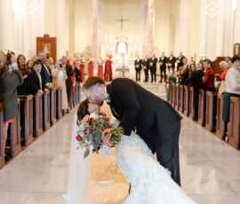 Bride and groom share a dramatic kiss at the Cathedral Basilica altar, surrounded by guests and their wedding party in Mobile.