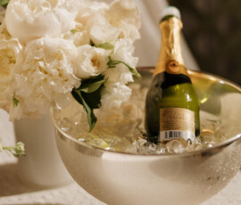 Champagne in an ice-filled silver bowl beside a white flower bouquet on a textured tablecloth at Battle House Mobile wedding.