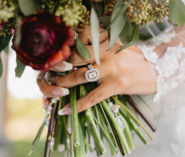 Bride’s hand with diamond ring holding rose and greenery bouquet at Mobile Alabama wedding, close-up shot.