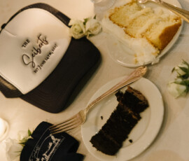 Wedding reception table with slices of vanilla and chocolate cake, candlelight, and custom “The Saiberts” wedding hat favor.