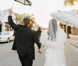 Bride and groom walk hand in hand with parasols at sunset after their Crown Hall wedding.