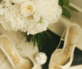 White bouquet behind elegant white heels with gold accents on tiled floor, prepared for a Mobile Cathedral wedding.