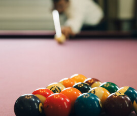 Racked billiard balls in focus on a pool table, blurred player aiming to break; lively Battle House wedding vibe.