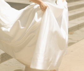 Bride in strapless white wedding dress lifts skirt, showing pointed heels outside Cathedral-Basilica in sunny Mobile.
