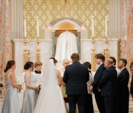 Bride and groom at the altar with their wedding party in a Cathedral-Basilica church, featuring elegant decor and crucifix.