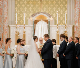 Bride and groom exchanging vows during a traditional church wedding ceremony beneath a crucifix.