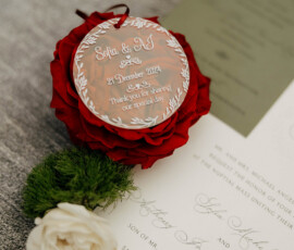 Wedding invitation close-up with elegant script, red and white flowers, and tag: Sofia & MJ, 21 December 2022, Cathedral Basilica Mobile.