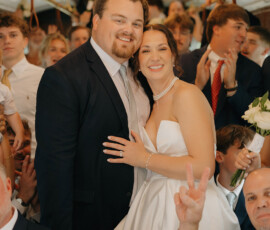 Bride and groom smile on a crowded trolley with loved ones after their Cathedral-Basilica wedding in Mobile. Joyful atmosphere.