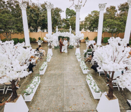 Elegant outdoor Louisiana wedding with white flowers, pillars, lush greenery, and a timeless aisle-side ceremony.