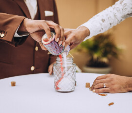 Two people in a brown suit and white lace pour colored sand into a jar, symbolizing unity at a Louisiana wedding ceremony.