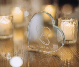 Heart-shaped glass keepsake engraved with The Richardsons, surrounded by candles on wood, evokes a cozy New Orleans wedding.