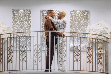 Newlywed couple embracing on an ornate balcony inside the wedding reception venue.