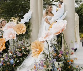 Wide view of outdoor gazebo ceremony with couple at the altar surrounded by wedding party and guests.