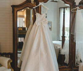 White wedding dress with large back bow and veil on wooden mirror in vintage room, Gulf South wedding inspiration.