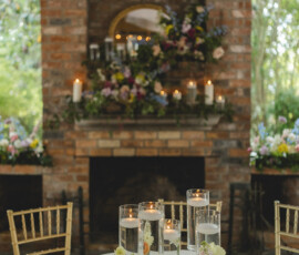 Round table with candles, flowers, gold chairs, and a fireplace—ideal for an intimate New Orleans wedding.