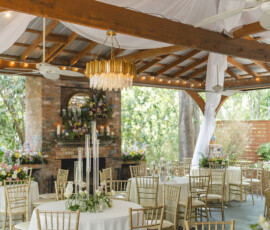 Outdoor wedding reception with white linens, gold chairs, floral centerpieces, and string lights under a pavilion in New Orleans.