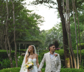 Bride and groom holding hands in a lush garden, surrounded by greenery—elegant New Orleans wedding inspiration.