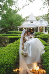 Couple sharing a kiss in front of a white vintage convertible during romantic garden wedding portraits.