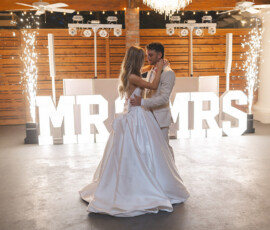 Bride and groom’s first dance in front of illuminated MR & MRS letters at their Louisiana wedding, with sparklers and chandelier.