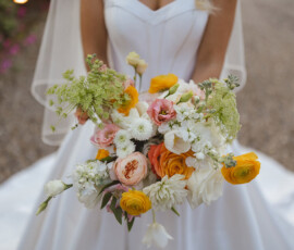 Bride in white dress holding a colorful bouquet on a gravel path at her Louisiana wedding.