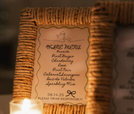 Framed wine menu for a Mobile Alabama wedding lists varietals beside a candle; bottom text: Please drink responsibly!.