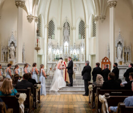 Bride and groom at church altar with wedding party, guests watching during a Louisiana ceremony.