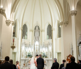Bride and groom at the altar in a grand Louisiana church as guests watch during their wedding ceremony.