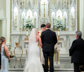 Bride and groom at a New Orleans church altar with two attendants, flowers, and candles—stunning Gulf South wedding inspiration.