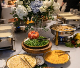 Buffet table with toppings, hot trays, and a white and blue floral arrangement for Gulf South wedding inspiration.