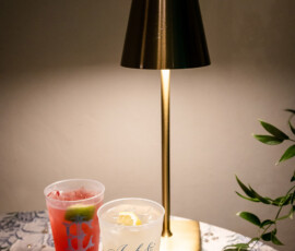 Red and yellow personalized cups with “Jack & Emily” on a floral tablecloth beside a gold lamp; green leaves on the right.