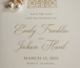 Gold and pearl earrings on a cream wedding invitation with church art and elegant text for Emily Franklin and Jackson Hamil.