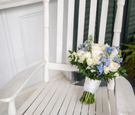 White rocking chair with white roses and blue flowers in lace on a porch; elegant Louisiana wedding inspiration.