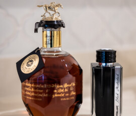 Blanton’s bourbon with horse stopper and Montblanc ink bottle on a white countertop, perfect for elegant wedding inspiration.