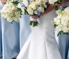 Bride in white gown with white and blue bouquet, surrounded by light blue bridesmaids—ideal Gulf South wedding inspiration.