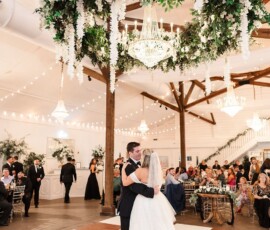 Bride and groom share their first dance under a floral chandelier in an elegant Louisiana wedding venue.