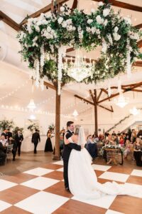 Bride and groom share their first dance under a floral chandelier in an elegant Louisiana wedding venue.