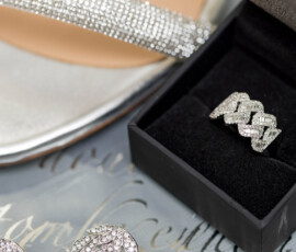 Diamond ring in black box, silver shoe, and rhinestone earrings on script background—New Orleans wedding inspiration.
