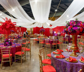 Banquet hall with red and purple flowers, gold chairs, and elegant table settings—ideal for a Louisiana wedding.