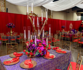 Banquet hall with red and purple drapes, gold chairs, elegant tablescapes—ideal for a chic Louisiana wedding reception.
