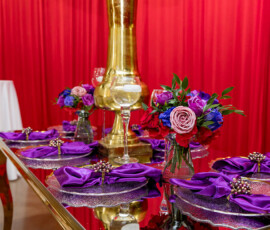 Elegant table with purple napkins, jeweled rings, gold centerpiece, and floral touches at a New Orleans wedding reception.