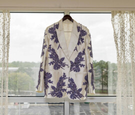 White blazer with purple floral patterns on hanger by window, perfect elegant wedding inspiration.