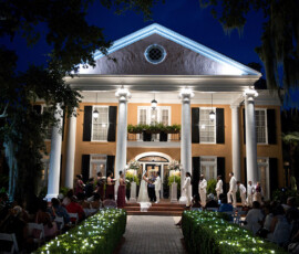 Nighttime wedding outdoors by a grand columned mansion, lights aglow—classic Louisiana Gulf South charm.