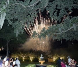 Fireworks illuminate a garden fountain as guests watch, evoking the magic of a New Orleans wedding celebration.