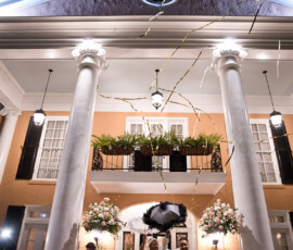 Grand white columns, greenery, and gold streamers set a magical scene for a classic New Orleans-inspired wedding celebration.