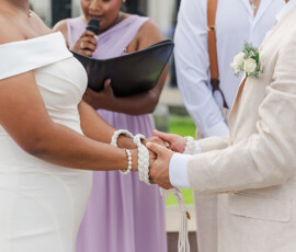 A couple with hands bound by a cord during a Louisiana wedding as an officiant reads, inspiring meaningful ceremonies.