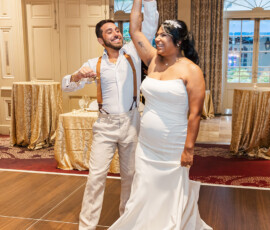 Smiling bride and groom dance at an elegant wedding with gold accents and chandelier, inspiring romantic celebrations.