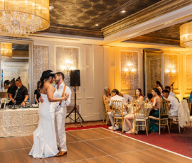 Bride and groom’s first dance at a Louisiana wedding, with guests, chandeliers, gold chairs, and DJ in background.